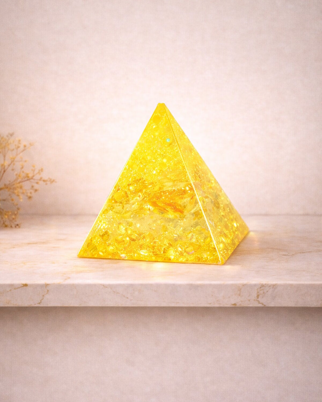 Three colorful pyramid-shaped crystal objects on a marble surface with a light background